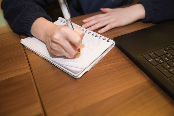 Gros plan de la femme assise au bureau et écrivant sur un carnet de notes au bureau
 - Photo, image