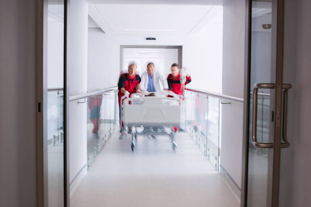 Artsen duwen noodgevallen brancard bed in gang in ziekenhuis - Foto, afbeelding
