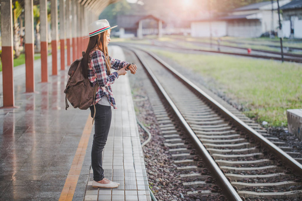 schöne junge asiatische Frau Reisende suchen Uhr mit brauner Tasche, wartet auf Zug am Bahnhof, chinesische Touristen, Reise-und Urlaubskonzept. - Foto, Bild