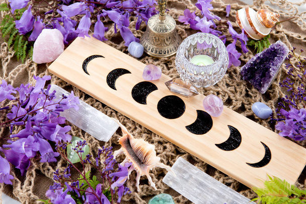 Bruja Pagana Fases de la Luna Altar con cristales de selenita y amatista, con velas y flores púrpura
 - Foto, imagen