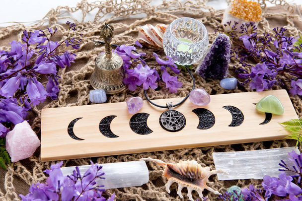 Luna llena bruja pagana fases lunares Altar con cristales de selenita y amatista, con velas, pentagrama y flores púrpuras
 - Foto, Imagen