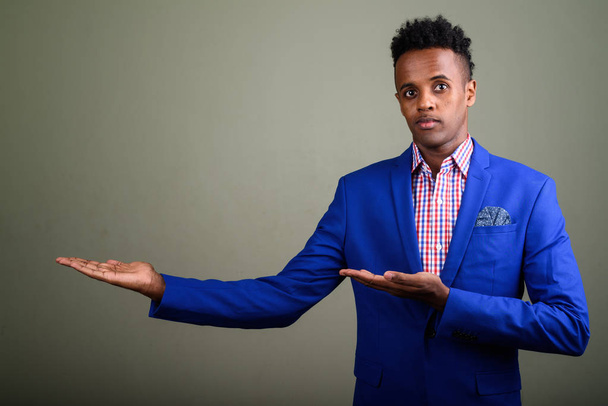 Jonge knappe Afrikaanse zakenman dragen pak tegen gekleurde  - Foto, afbeelding