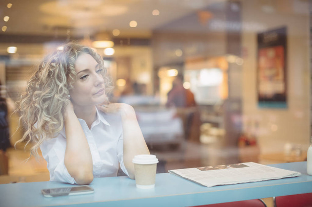 Pensativa mujer de negocios sentada en el mostrador en la cafetería
 - Foto, imagen