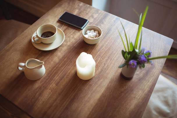 Κινητό τηλέφωνο και φλιτζάνι καφέ στο ξύλινο τραπέζι στην καφετέρια - Φωτογραφία, εικόνα