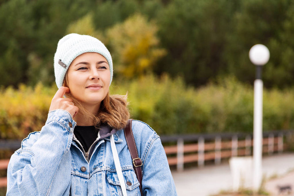 Romantic Young Woman on autumn  Natural Background Outdoors. Pensive smiling girl  in white knitting hat,  denim coat, shirt  posing in  seafront - Fotografie, Obrázek