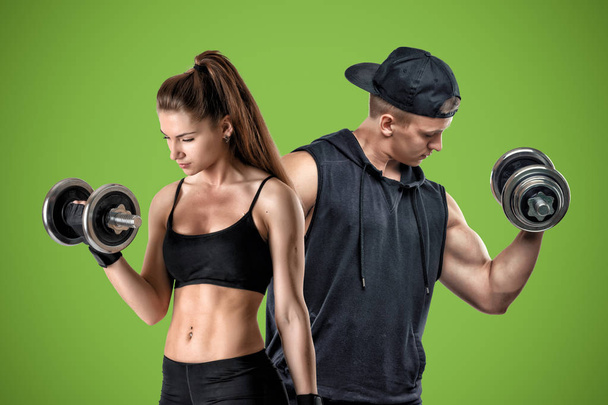 A young muscular woman and a fit man stand on a green background. - Foto, afbeelding