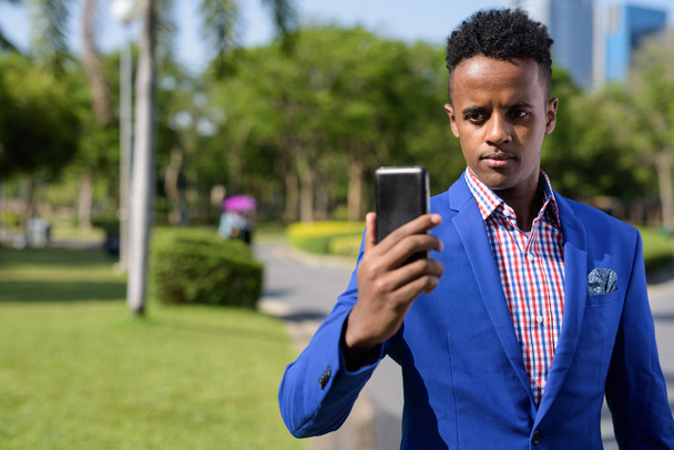 Молодой привлекательный африканский бизнесмен пользуется мобильным телефоном
 - Фото, изображение
