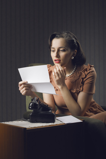 Young woman reading a letter sitting on armchair - Photo, image