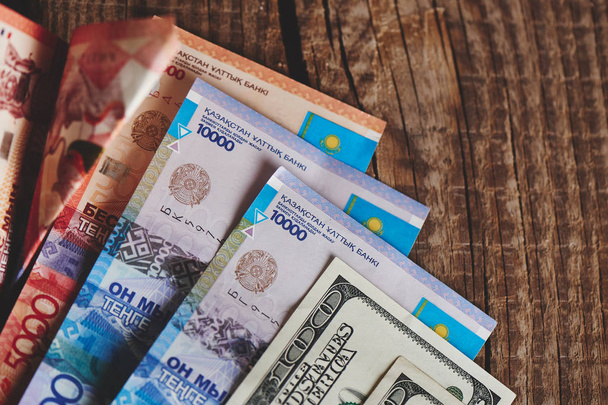 pile of American dollars and kazakh tenge on wooden background, close-up  Business and Finance concept  - Foto, Imagen