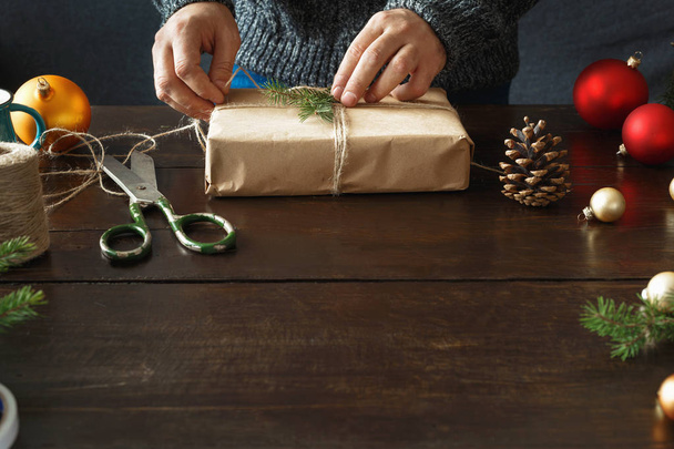 Male hands preparing christmas gift on wooden table. Christmas background - Foto, immagini