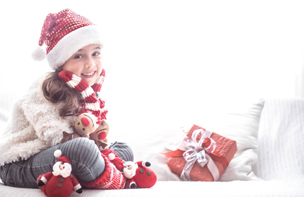 Little cute girl with Christmas gift in Santa costume on sofa, Christmas and new year concept - Photo, Image