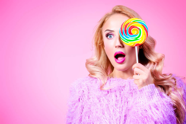 A portrait of a fashionable bright lady posing in studio with colorful lollipop. Fashion for women. Pink colors. - Foto, Imagen