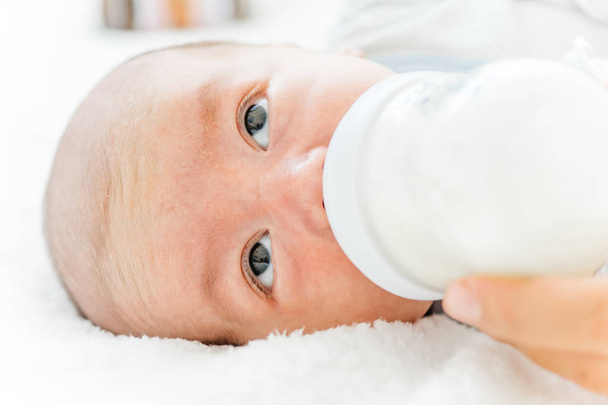 moeder haar baby te voeden met een formule melk uit een fles - Foto, afbeelding