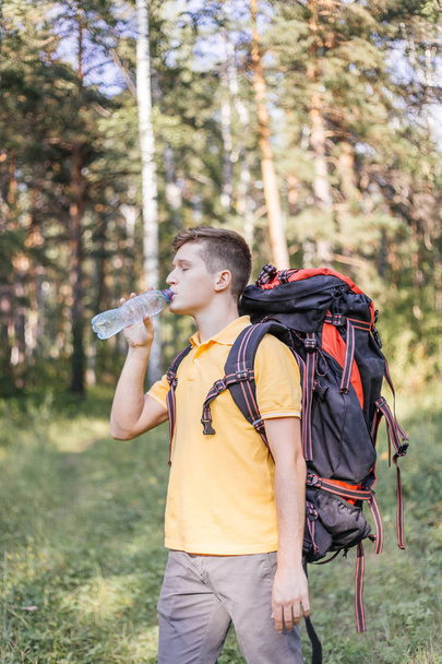 Hiker tourist guy is drinking water from a bottle - Foto, imagen