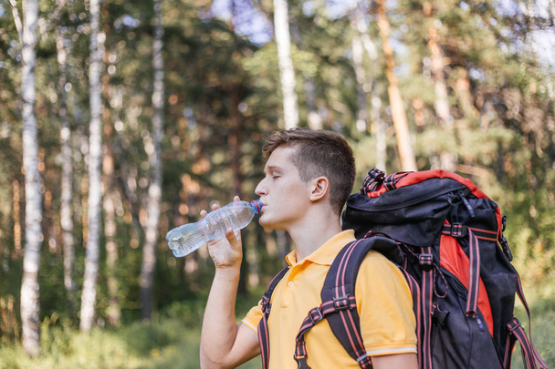 Hiker tourist guy is drinking water from a bottle - 写真・画像