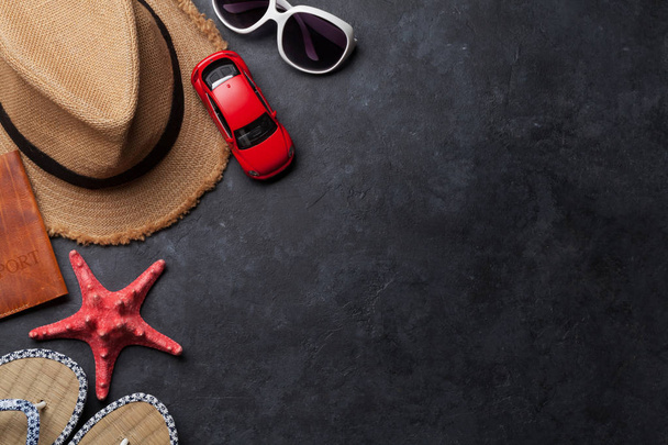 Reizen vakantie achtergrond concept met hoed, zonnebril, zeesterren en auto speelgoed op stenen achtergrond. Bovenaanzicht met kopie ruimte. Plat leggen - Foto, afbeelding