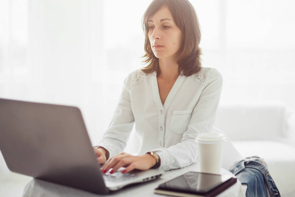 Freelancer käyttäen kannettavan, nainen työskentelee kannettavan tietokoneen kirjoittamalla näppäimistön kotona
 - Valokuva, kuva