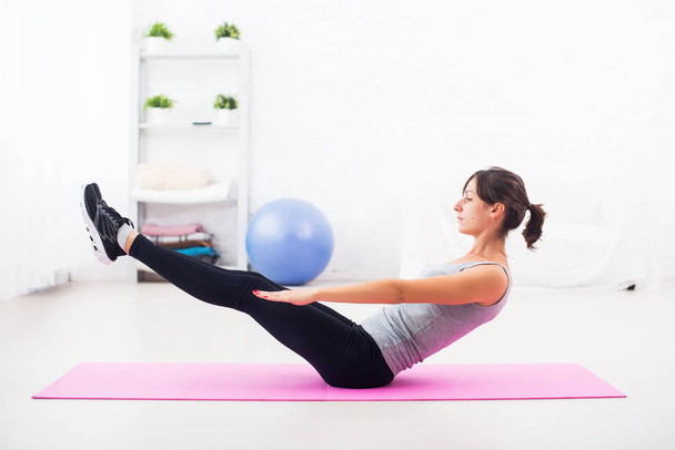 Vrouw doen buik oefening op mat thuis sport uitrekken pilates yoga fitness, opleiding. - Foto, afbeelding
