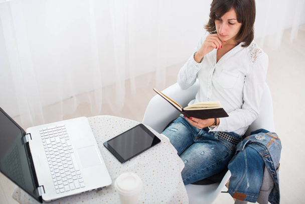 zakenvrouw met laptop en dagboek in een heldere office freelance werk thuis. - Foto, afbeelding