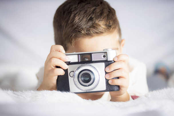 Όμορφο αγόρι με μια φωτογράφηση φωτογραφική μηχανή στο κρεβάτι - Φωτογραφία, εικόνα