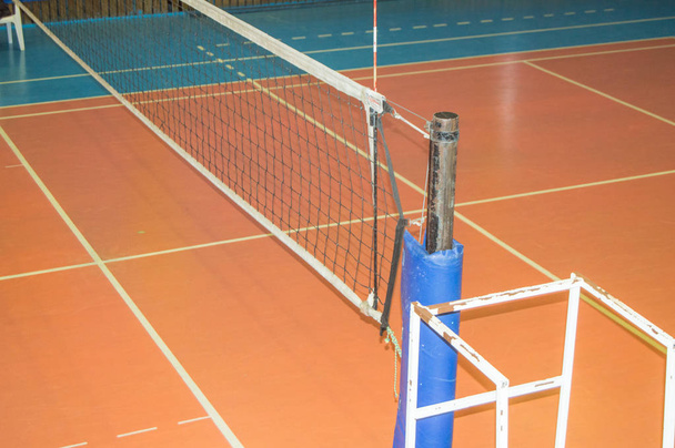 Sala de deportes vacía con una red de voleibol estirada y una torre para el juez - Foto, imagen