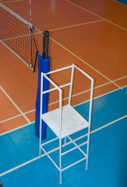 Lege sporthal met een uitgestrekt volleybalnet en een toren voor de keurmeester - Foto, afbeelding