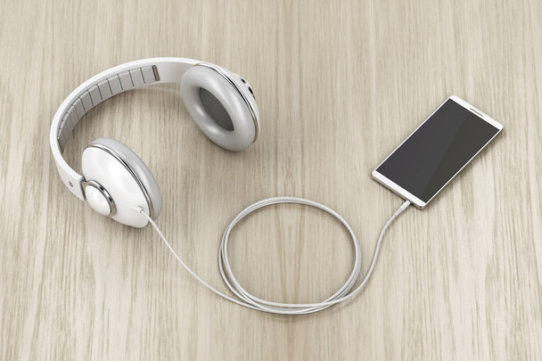 Velká drátová sluchátka a smartphone s prázdným displejem na dřevěném stole - Fotografie, Obrázek