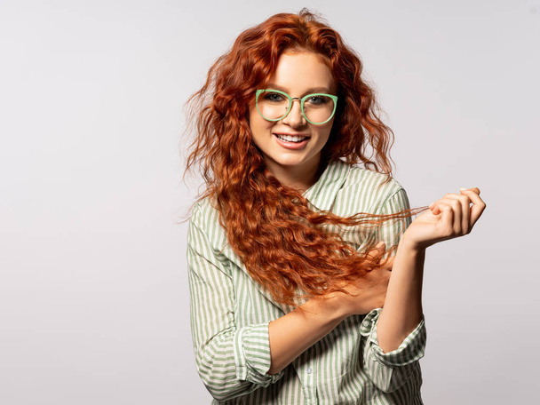 Portrait of cheerful young curly woman on light background - Photo, image