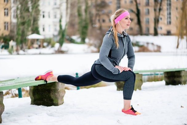 Γυναίκα, τεντώνοντας τα άκρα της για την άσκηση αθλητικών το χειμώνα - Φωτογραφία, εικόνα