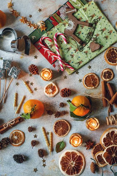 New Year or Christmas composition with tangerines, dry oranges, cinnamon, gifts, candies and toys on light rustic table - Fotó, kép