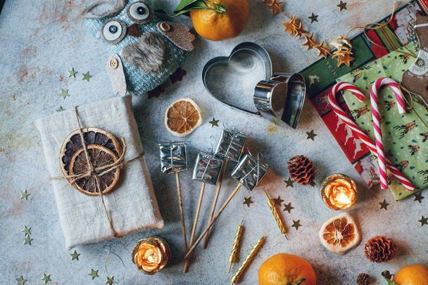 New Year or Christmas composition with tangerines, dry oranges, cinnamon, gifts, candies and toys on light rustic table - Photo, image