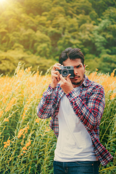 Young hipster man taking photo with old style camera with nature landscape background. Retro and vintage photography concept. - Fotoğraf, Görsel
