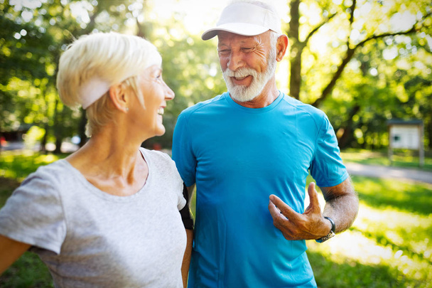Senior couple jogging and running outdoors in nature - Photo, Image