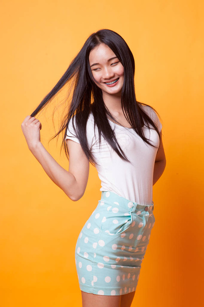 Portrait of beautiful young Asian woman on bright yellow background - Foto, Imagen