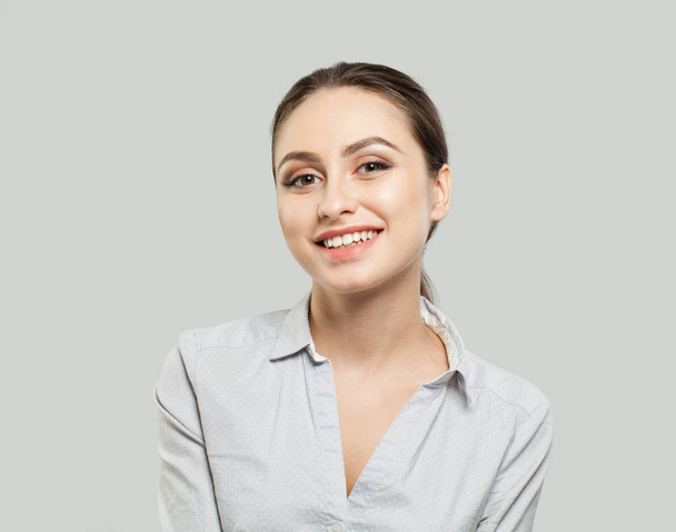Vriendelijke jonge vrouw die lacht op witte achtergrond - Foto, afbeelding