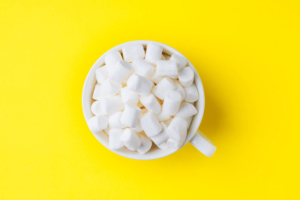 Marshmallow in a mug on a yellow background. The concept of Christmas and New Year - Fotografie, Obrázek