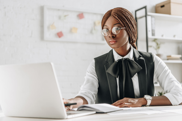 atraktivní zaměřil afrických amerických dospělých podnikatelka v brýlích sedí u počítače, recepce a práci v kanceláři - Fotografie, Obrázek