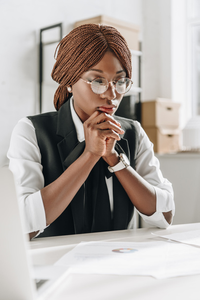 nachdenkliche afrikanisch-amerikanische Architektin in Brille, die im Büro an Dokumenten arbeitet - Foto, Bild