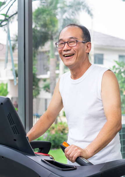 Starszy człowiek ćwiczenia na bieżni w centrum fitness. Dojrzałe zdrowego stylu życia. - Zdjęcie, obraz