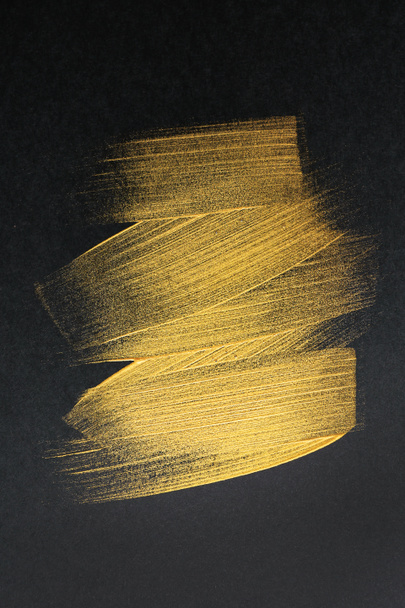 Strokes of gold paint on dark background - Fotoğraf, Görsel