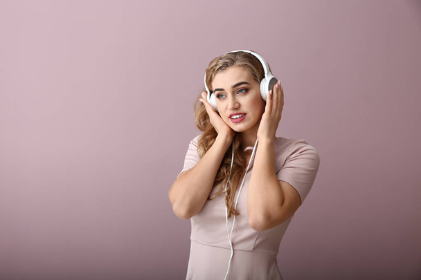 Beautiful young woman listening to music on color background - Foto, afbeelding