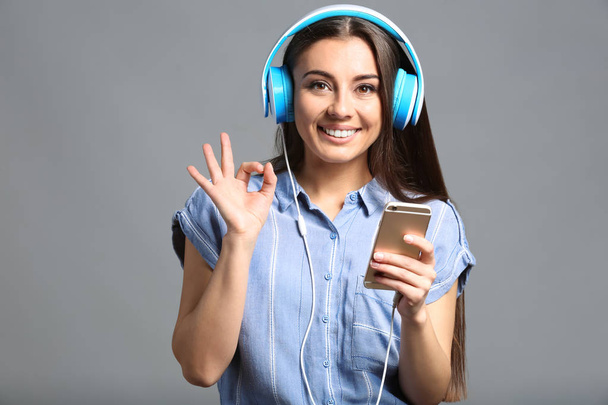 Mooie vrouw luisteren naar muziek op een grijze achtergrond - Foto, afbeelding