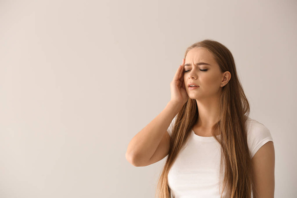 Fiatal nő szenved fejfájás-ra könnyű háttér - Fotó, kép