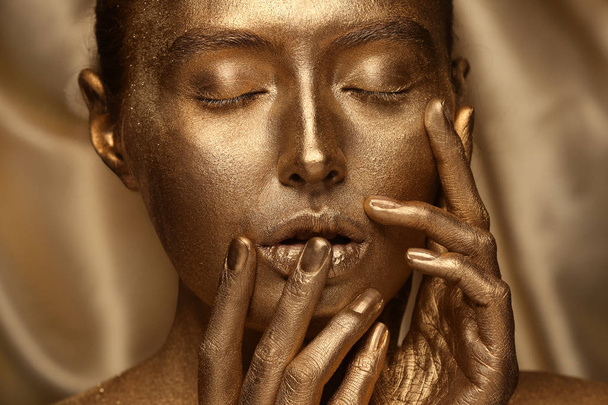 Krásná mladá žena s zlatou malbou na tělo proti barevné pozadí, closeup - Fotografie, Obrázek