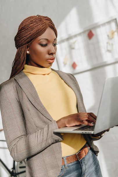serious african american adult businesswoman using laptop at workplace - Φωτογραφία, εικόνα