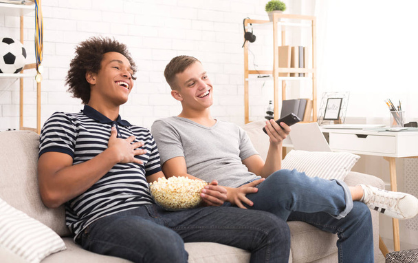 Два счастливых подростка смотрят комедийный фильм по телевизору
 - Фото, изображение