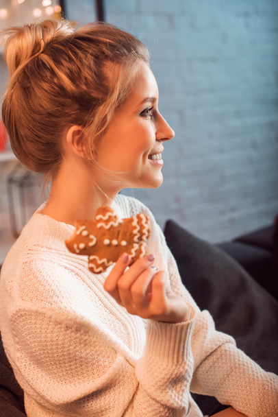 portrait of beautiful young blonde woman posing with gingerbread cookie - Fotó, kép
