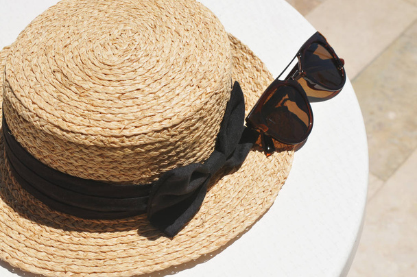 Straw hat with black bow and dark sunglasses - Valokuva, kuva