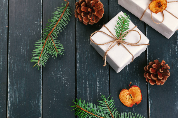 Новорічна композиція різдвяних подарунків з сосновими шишками та ялиновими гілками на дерев'яному фоні
 - Фото, зображення