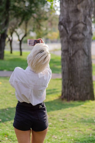 Young girl takes selfie  in the park. - Zdjęcie, obraz